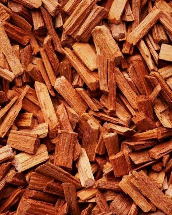 A close-up of a pile of small, reddish-brown sandalwood chips. The image, with its focus on the natural wood texture, represents a scent that is smooth and grounding, anchoring the emotions while adding warmth and depth to mindful spaces.
