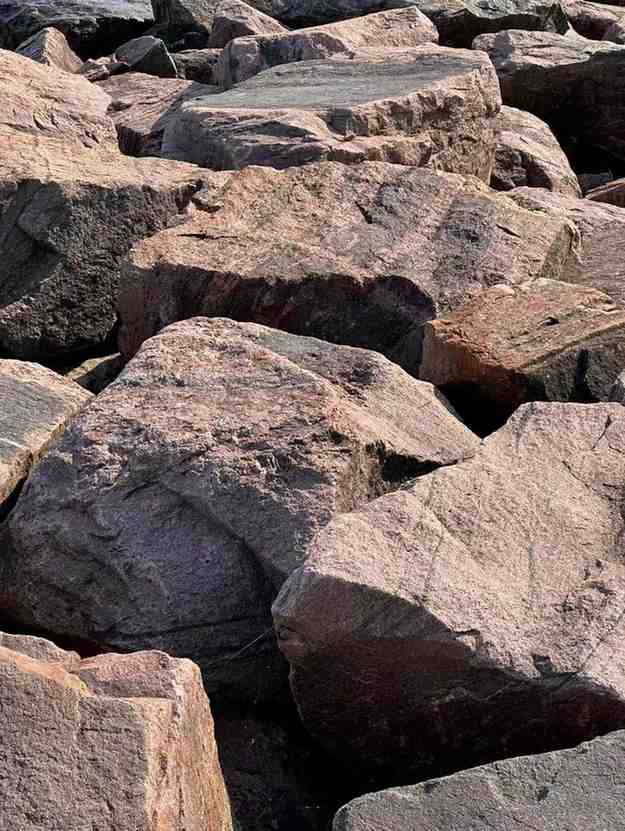 Large rugged rocks stacked together under sunlight, their rough surfaces evoking grounding strength — a natural reminder to clear the energy.