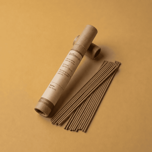 Palo santo incense sticks named ‘palo santo’ packed in an incense kraft paper tube labeled 'inflowence' on a orange background