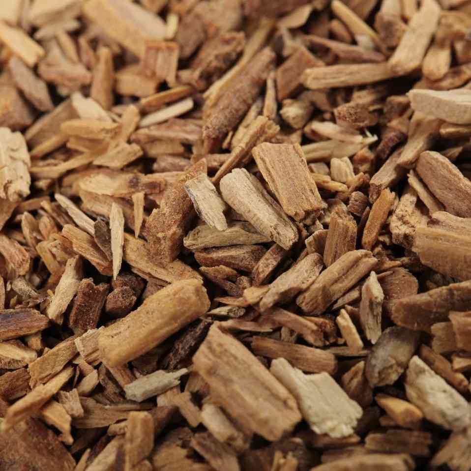 A close-up of a pile of small, light brown sandalwood chips. The image, with its focus on the natural wood texture, represents a scent that is smooth and grounding, anchoring the emotions while adding warmth and depth to mindful spaces.