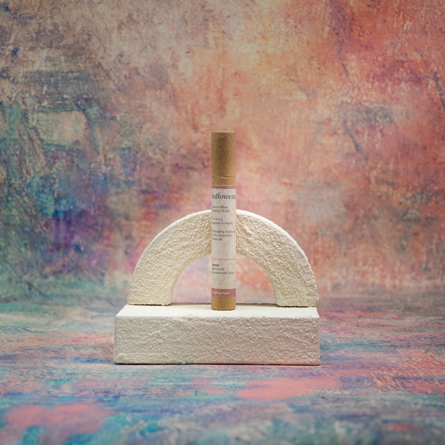 Blushing Rose incense tube displayed with white textured decor in front of a Claude Monet–inspired canvas — a serene, romantic composition that highlights the gentle elegance of the scent.