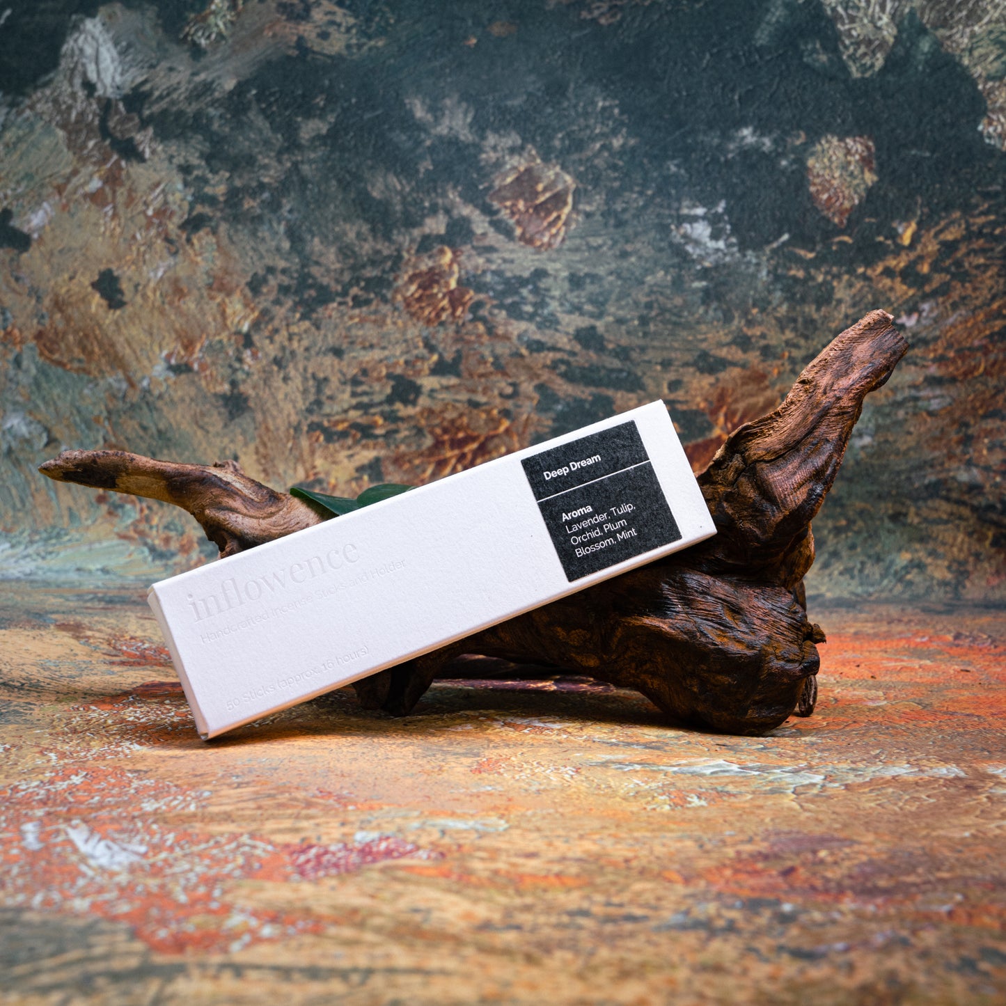 Deep Dream incense box styled with natural wood and greenery, set against a green, red, and yellow oil painting–inspired backdrop — evoking a warm, earthy ritual atmosphere.