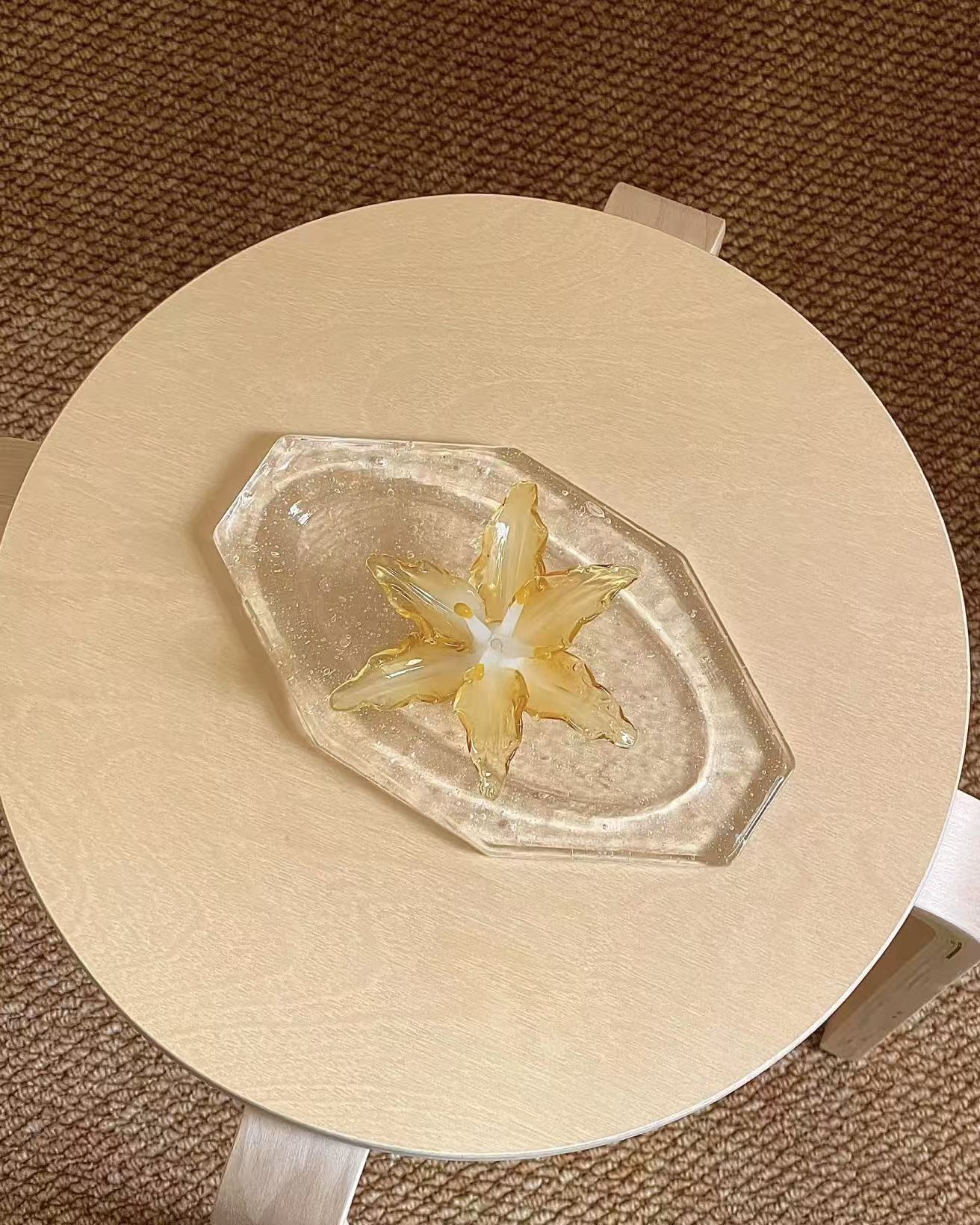 Lily glass incense holder placed on a glass ash tray, styled on a small wooden table to show scale and placement