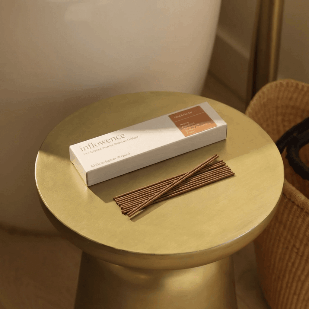 inflowence Petal & Nectar flower incense box with neatly arranged incense sticks on a round gold side table, styled in a warm minimalist interior, a mood-uplifting floral incense blend