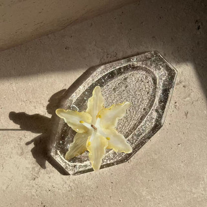Lily glass incense holder placed on a handcrafted glass ash tray, shown from above as part of a calm incense ritual setup