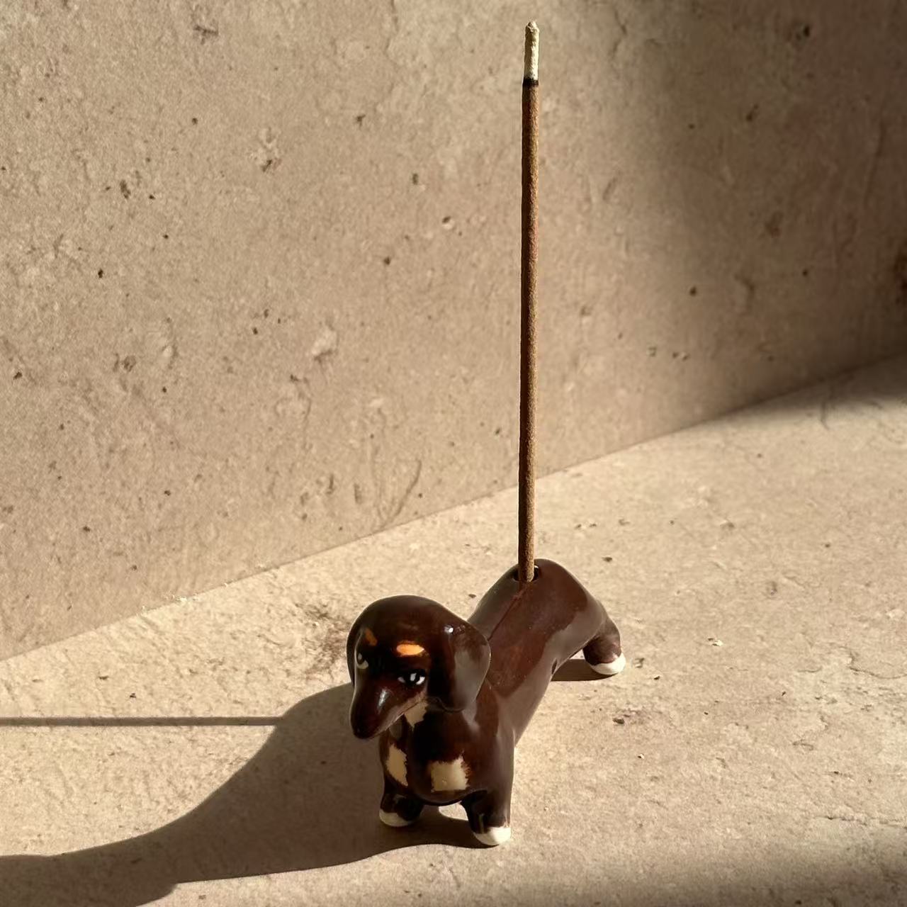 Hand-painted ceramic incense holder shaped like a dachshund, designed to hold incense sticks as a playful decorative accent
