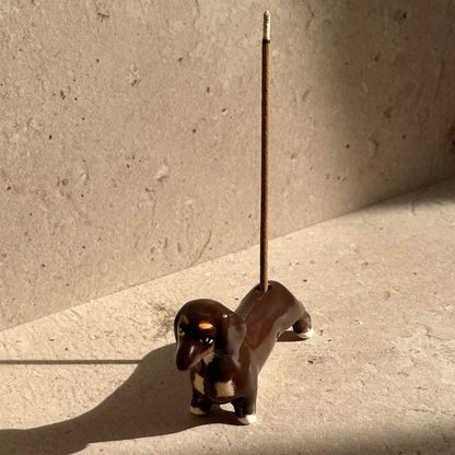 Hand-painted ceramic incense holder shaped like a dachshund, designed to hold incense sticks as a playful decorative accent