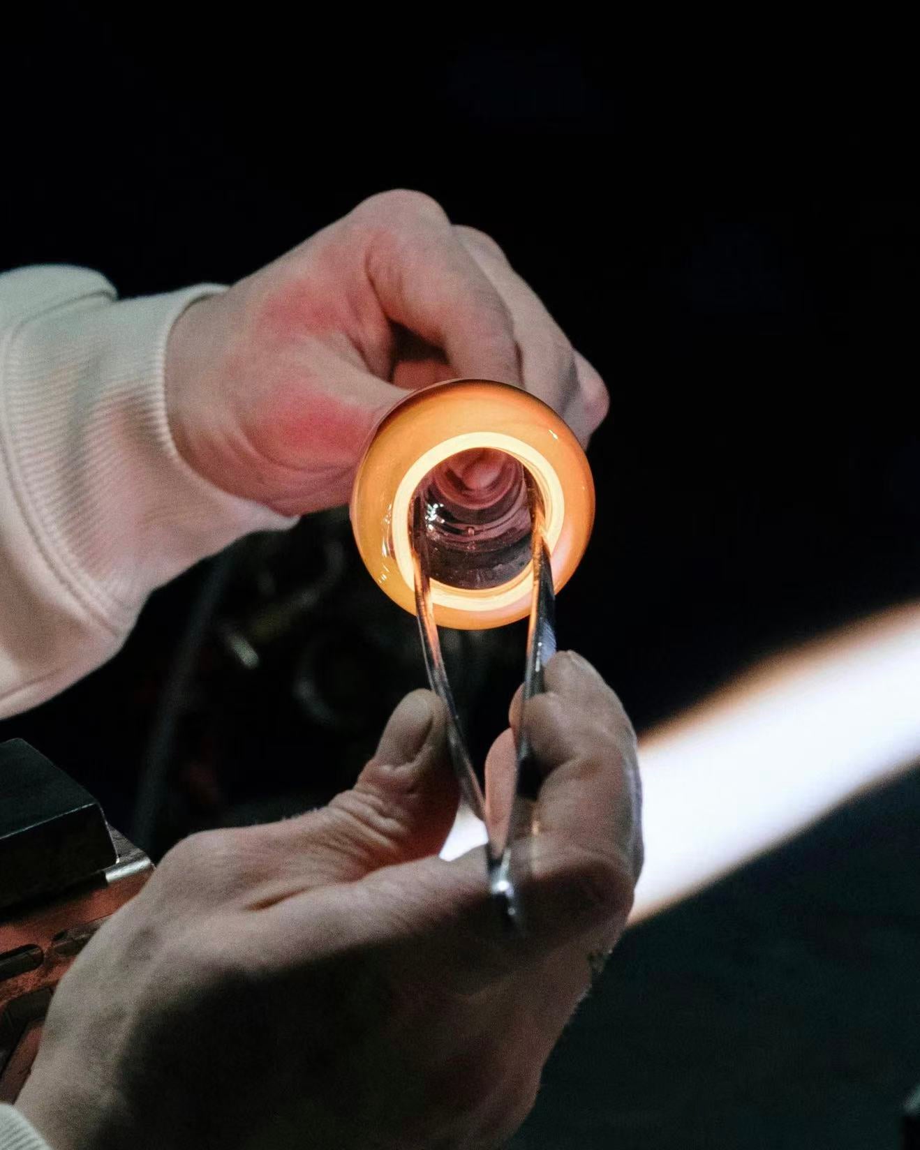 Artisan hands shaping molten glass during the making of a handcrafted glass incense holder, highlighting one-of-a-kind craftsmanship
