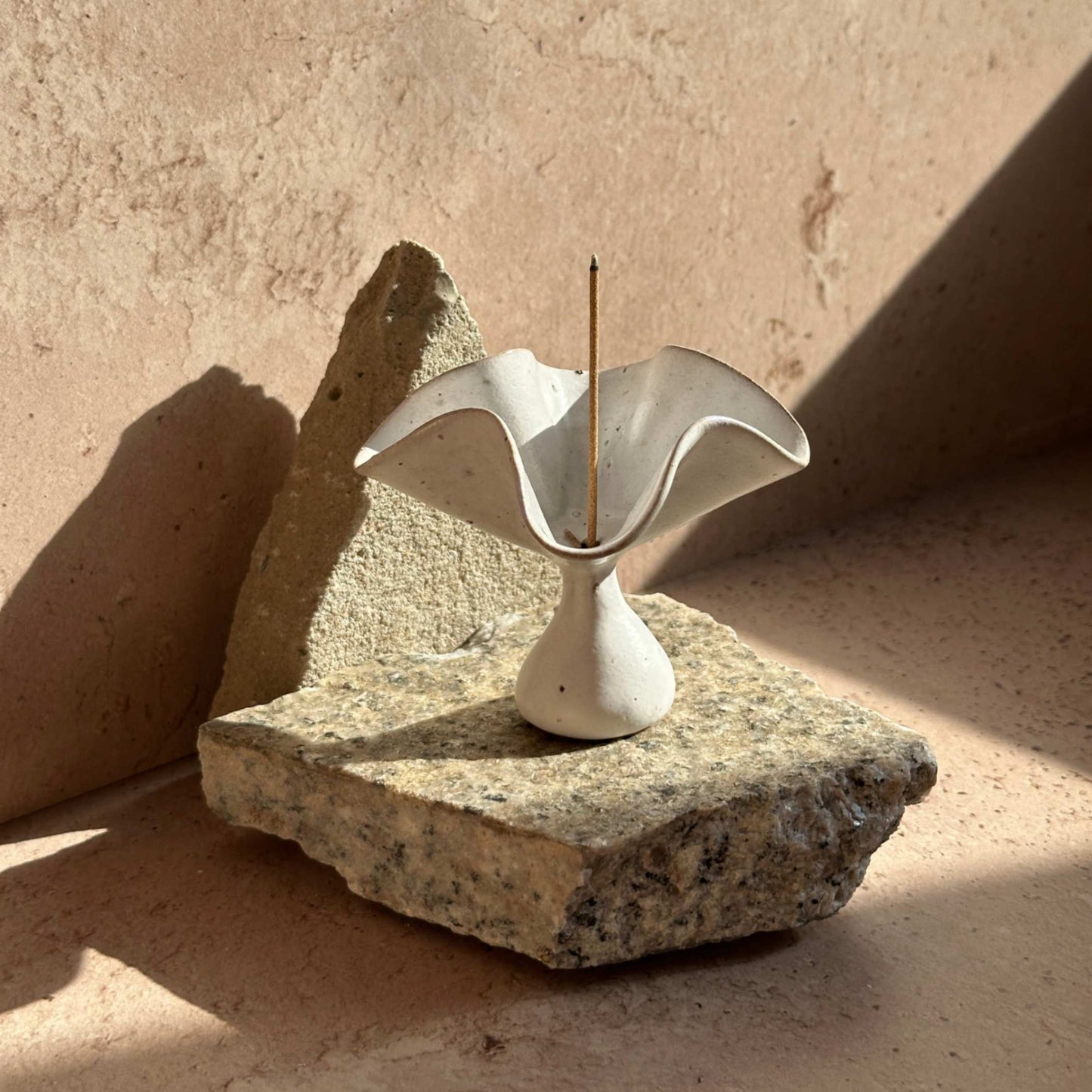 Handcrafted ceramic petal incense holder placed on natural stone, featuring softly folded edges and a sculptural form inspired by blooming petals.