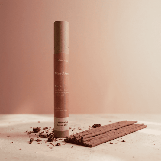 Paper kraft tube labeled 'Naked Rose' with rose incense sticks and dry rose petals on a beige background