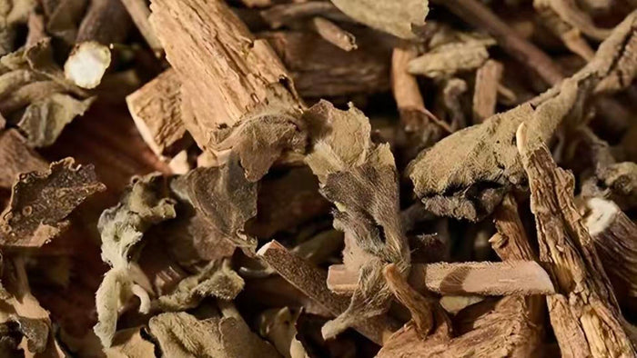 A close-up of dried botanical patchouli roots and bark pieces, showing their natural texture and earthy tones.