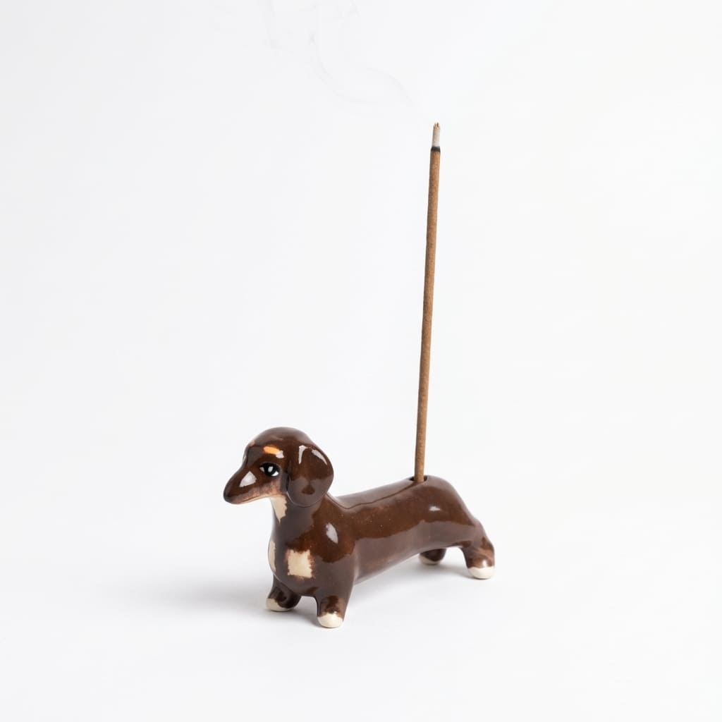 Sausage Dog Incense Holder product shot on a clean white background, featuring a compact hand-painted ceramic incense holder shaped like a dachshund with a lit incense stick placed in its back.