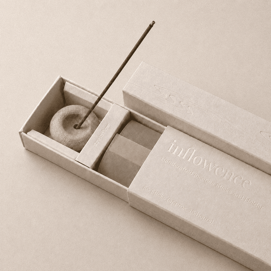 Close-up of an open inflowence incense box with a ceramic holder and a lit incense stick on a grey background.