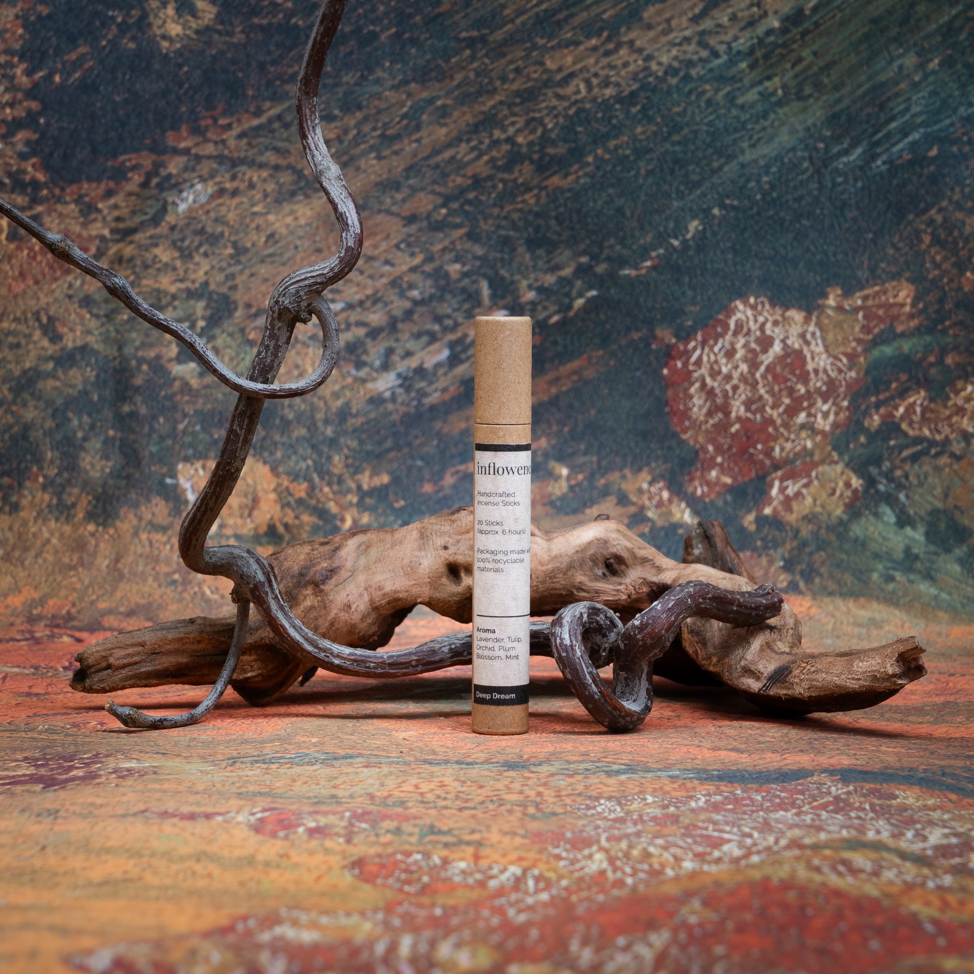 Deep Dream incense tube styled with natural wood and branches, set against a green, red, and yellow oil painting–inspired backdrop — evoking a warm, earthy ritual atmosphere.