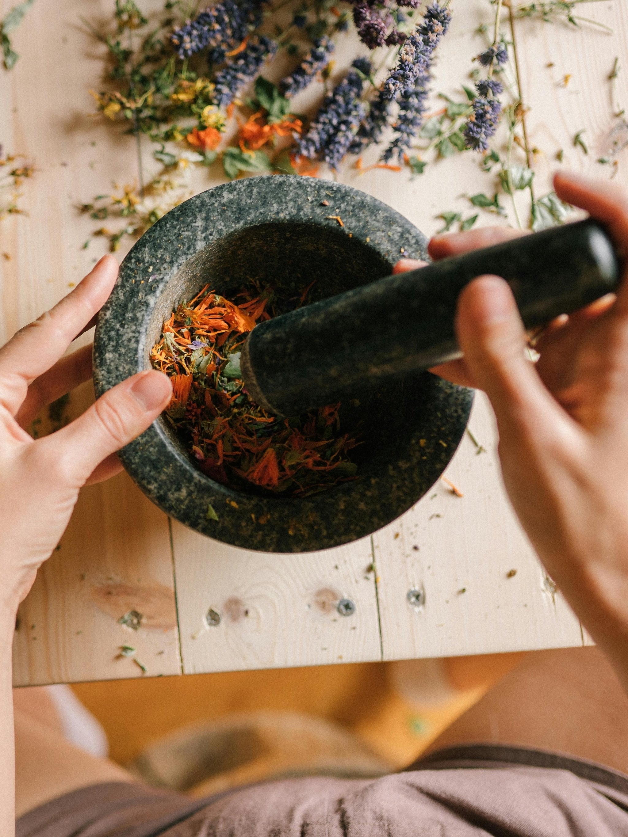 Close-up of a hand using a mortar and pestle with natural ingredients, symbolizing the handcrafted, small-batch process behind inflowence incense.