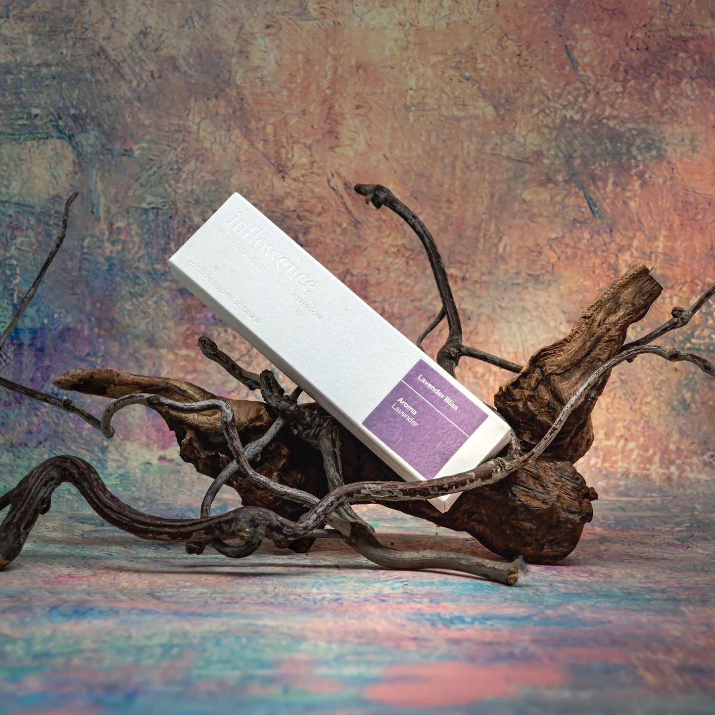 Lavender Bliss incense box resting on natural wood with delicate branches, set against a Claude Monet–inspired canvas — a dreamy, floral scene evoking soft beauty and ritual calm.