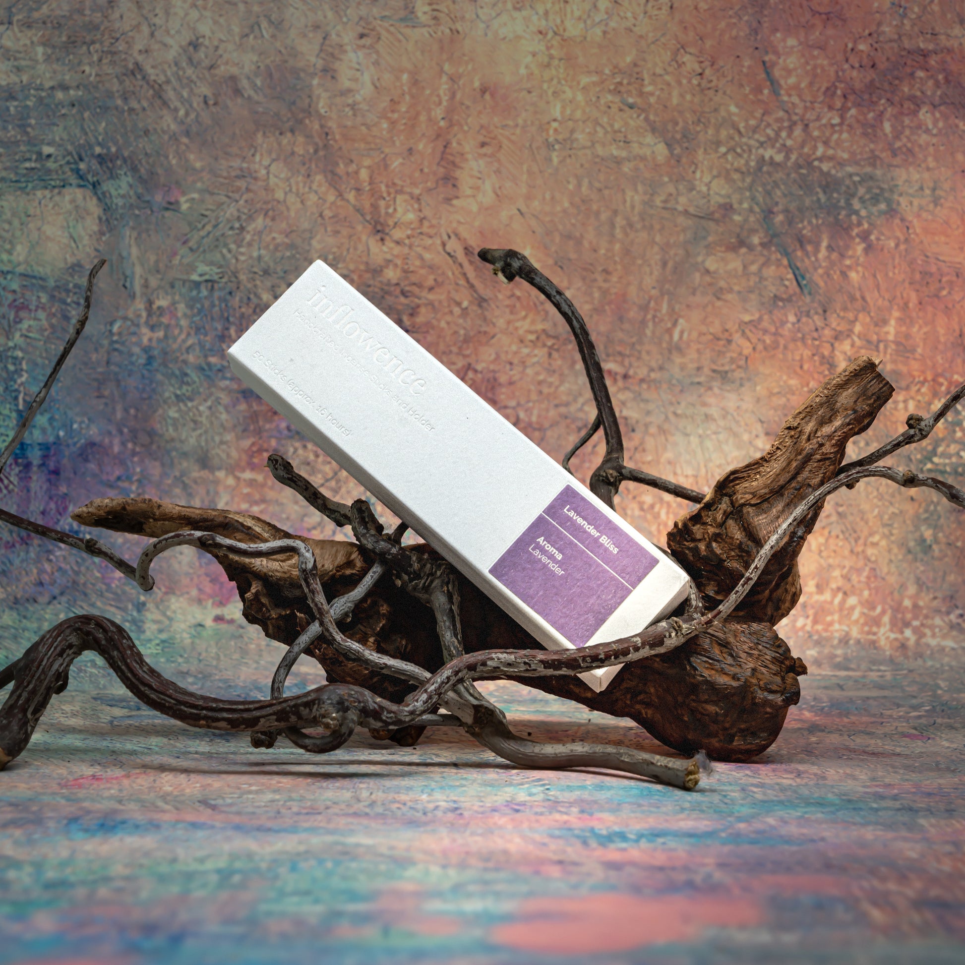 Lavender Bliss incense box resting on natural wood with delicate branches, set against a Claude Monet–inspired canvas — a dreamy, floral scene evoking soft beauty and ritual calm.