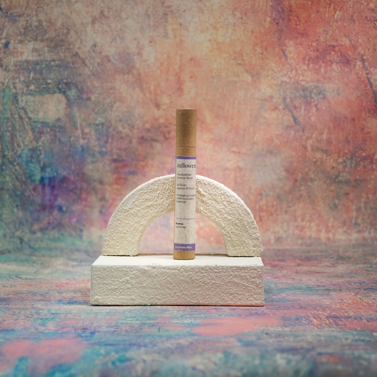 Lavender Bliss incense tube displayed with white textured decor in front of a Claude Monet–inspired canvas — a serene, romantic composition that highlights the gentle elegance of the scent.